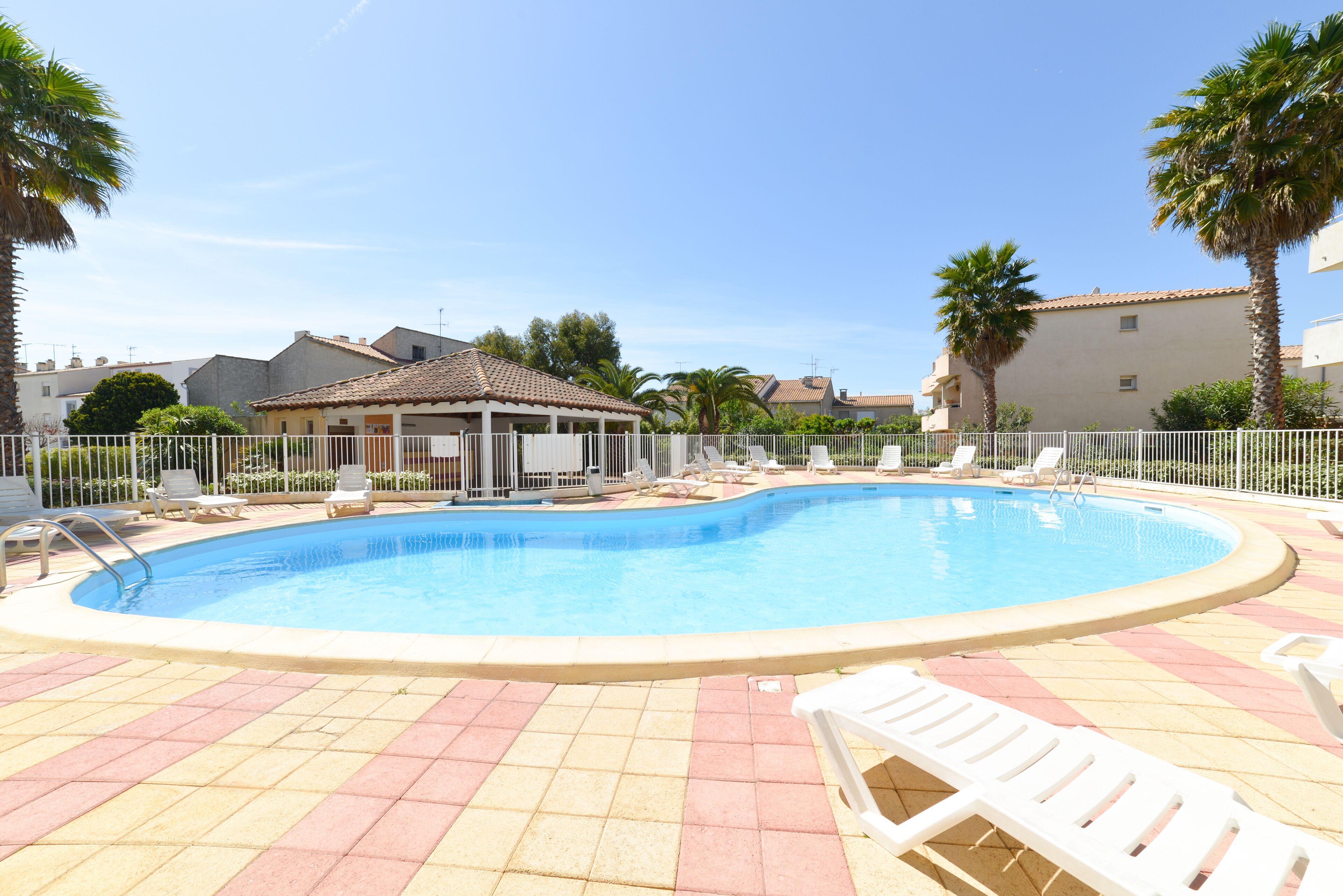 A swimming pool with lounge chairs and a small pavilion.