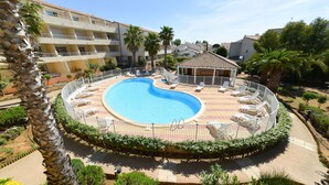 A circular swimming pool with a surrounding deck, palm trees, and a small gazebo. - Résidence Residhotel Le Mayflower (Le Grau-Du-Roi)