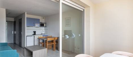 A modern apartment with a kitchen, dining area, and a balcony with a sliding glass door.