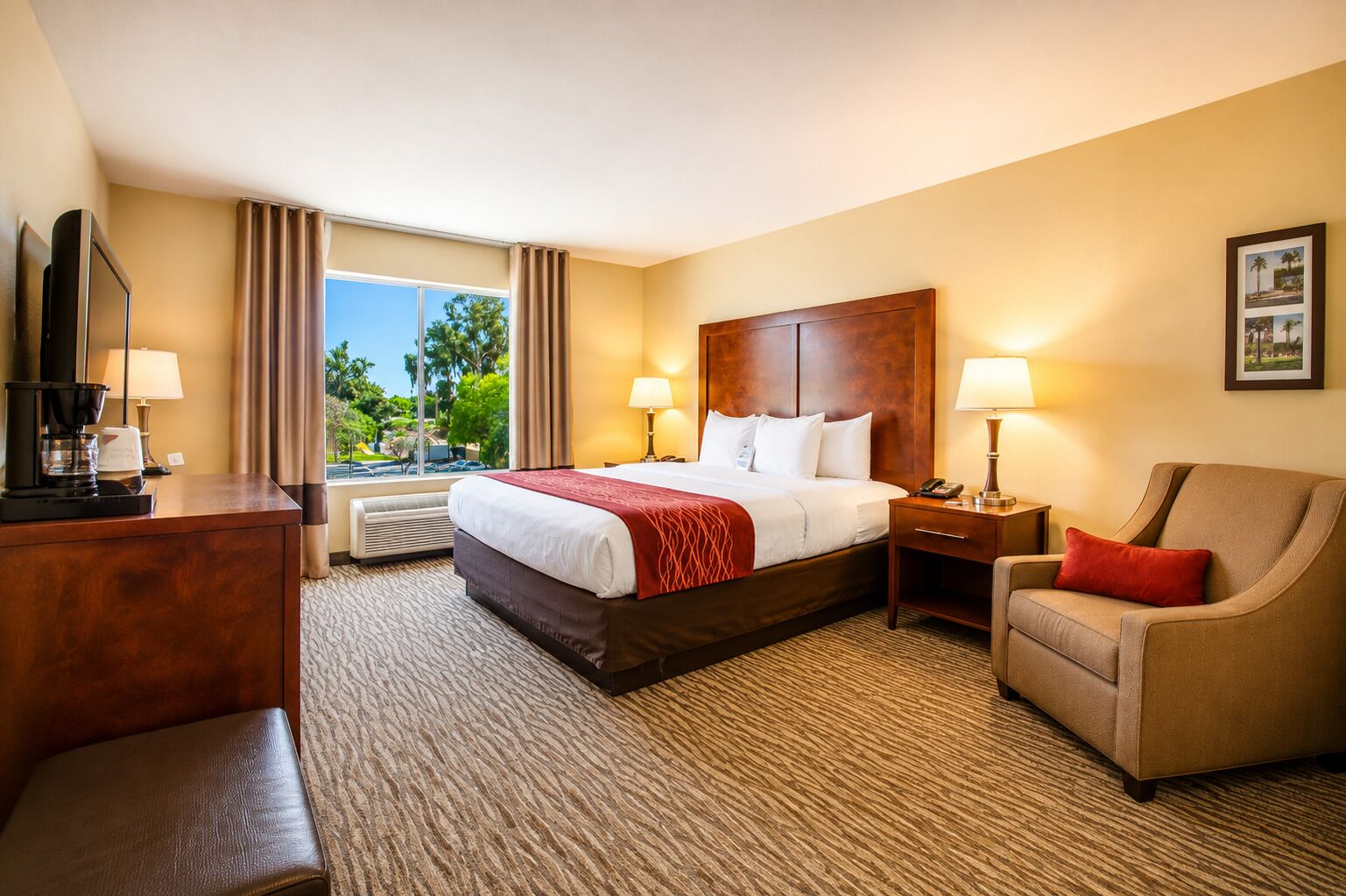 A hotel room with a bed, a desk, a chair, and a large window with curtains.