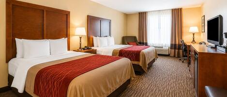 A hotel room with two beds, a desk, a television, and a chair.