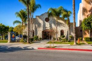 A stone building with a sign for Comfort Inn, surrounded by palm trees and a red curb.