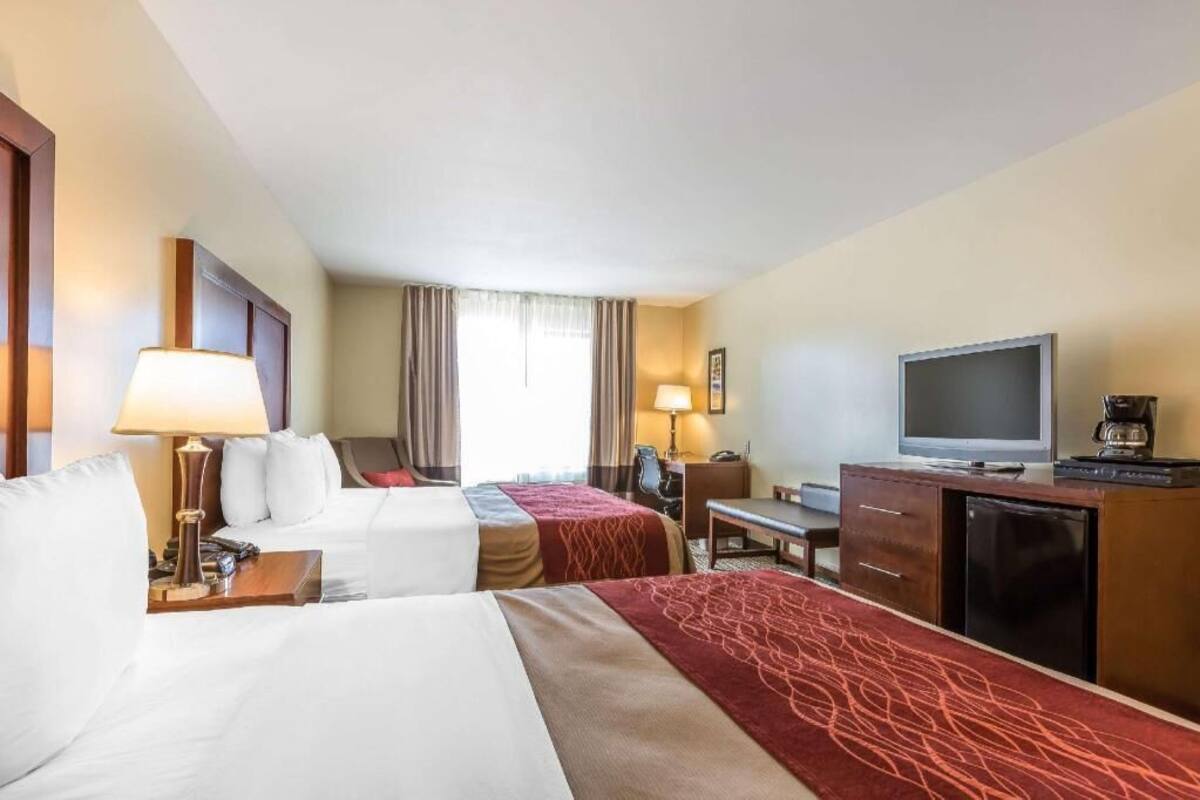 A hotel room with two beds, a desk, a television, and a coffee maker.