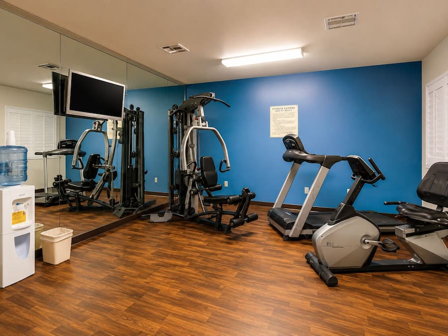 Une salle de sport équipée de matériel d’exercice, d’un distributeur d’eau et d’un miroir.