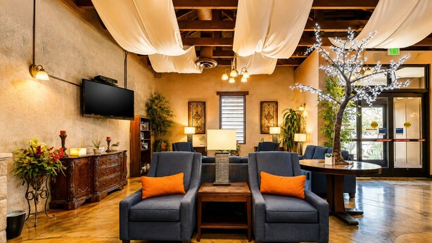 A lobby with two armchairs, a wooden coffee table, a television, and a reception desk.
