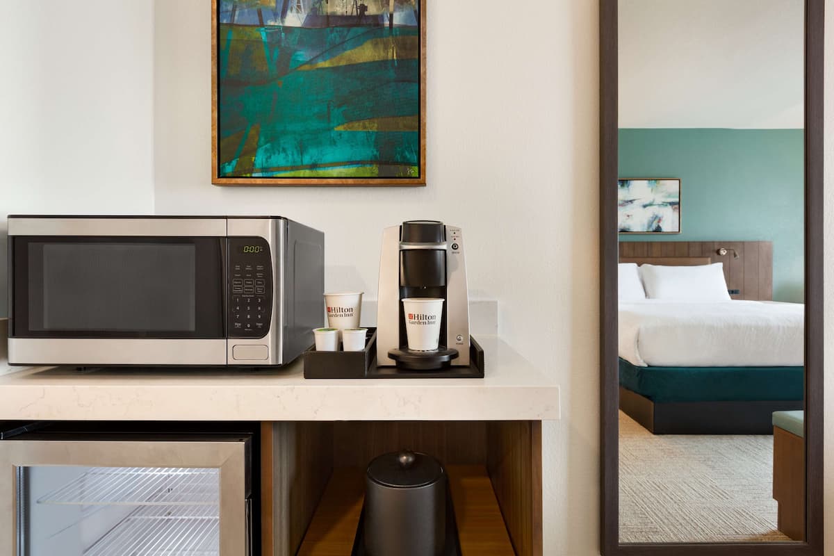 A hotel room with a microwave, coffee maker, and a small refrigerator on a counter.