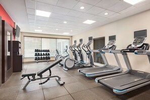 A gym with treadmills, elliptical machines, and dumbbells.