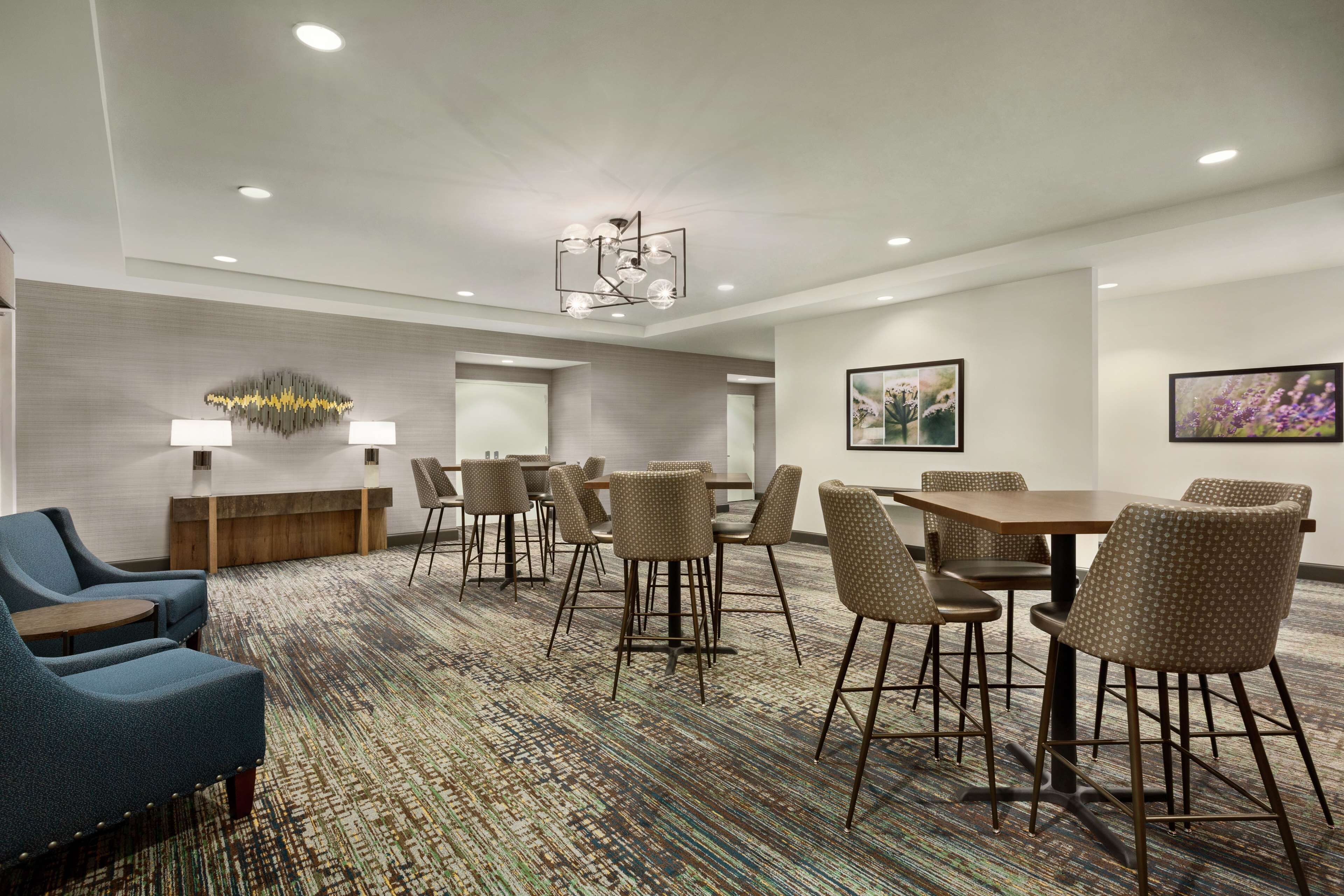 A hotel conference room with a patterned carpet, a wooden reception desk, and a modern chandelier.