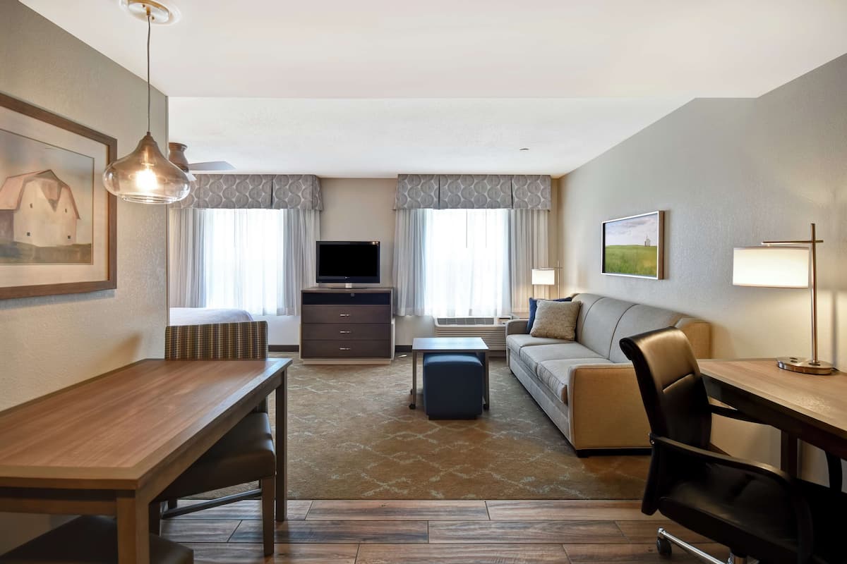 Een hotelkamer met een houten bureau, een bank, een televisie en een lamp.