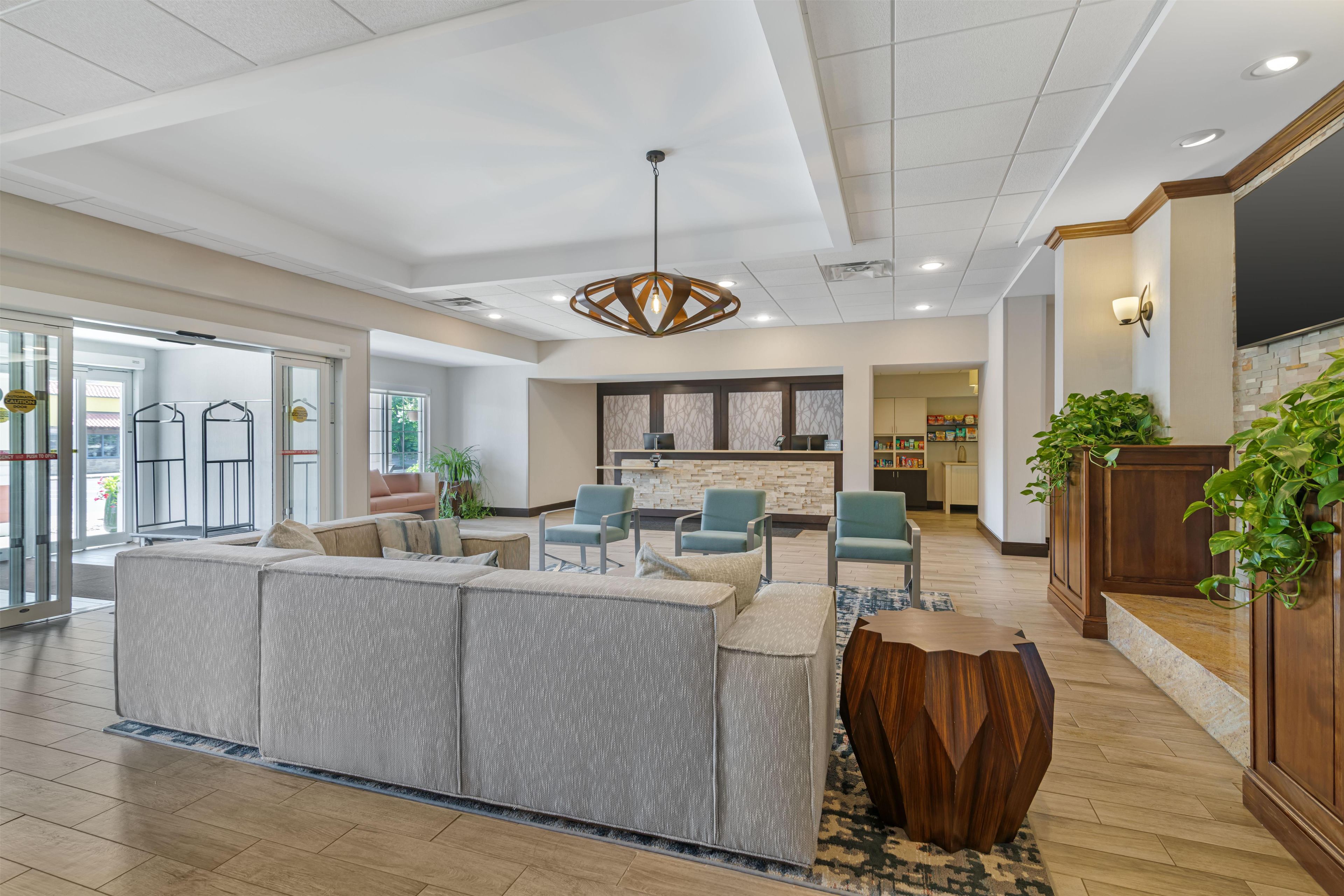 A hotel lobby with a seating area, a reception desk, and a large wooden coffee table.