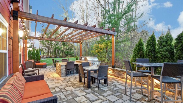 Un patio exterior con pérgola, mobiliario y zona de barbacoa.