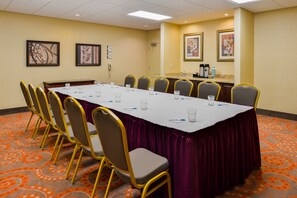 A conference room with a long table, chairs, and a reception area with a counter and framed pictures.