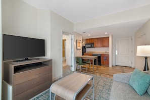 Een moderne woonkamer met een flatscreen televisie, een bank en een klein tafeltje.