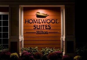 A hotel entrance with the sign "Homewood Suites Hilton".