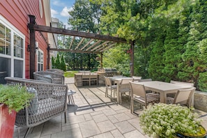 An outdoor patio with a pergola, seating, and a grill area. - Homewood Suites by Hilton Dover (Dover)