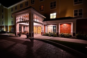 Entrada de um hotel com fachada bem iluminada, placa com a inscrição 