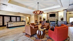 Un vestíbulo con mostrador de recepción, zona de estar con sillones, chimenea y televisor.
