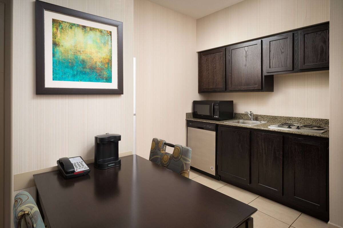 A modern kitchen with dark wood cabinets, a microwave, and a coffee maker on a dark countertop.