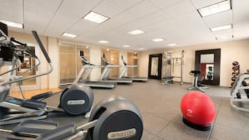 A gym with treadmills, elliptical machines, and exercise balls.