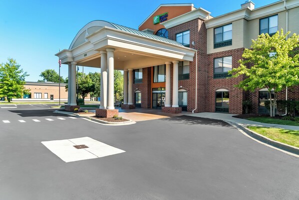 A hotel entrance with a covered driveway, brick facade, and a sign indicating it's a Holiday Inn Express. - Holiday Inn Express Hotel & Suites Detroit-Novi by IHG (Novi)