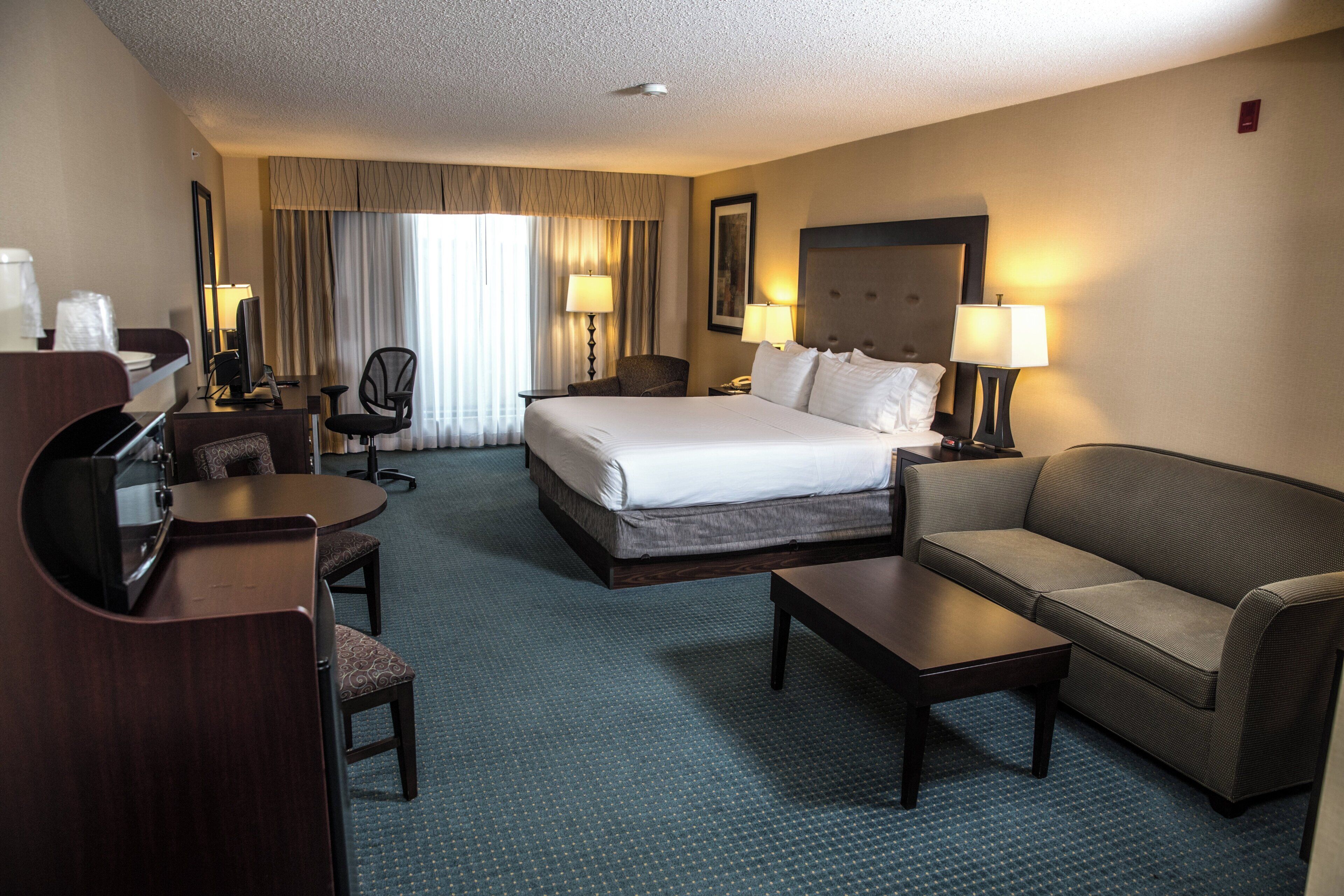 Une chambre d’hôtel avec un grand lit, un canapé, un bureau et une chaise.