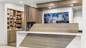 A hotel reception desk with a modern design, including a wooden reception counter and a blue wall with geometric patterns. - Holiday Inn Express Hotel & Suites Detroit-Novi by IHG (Novi)