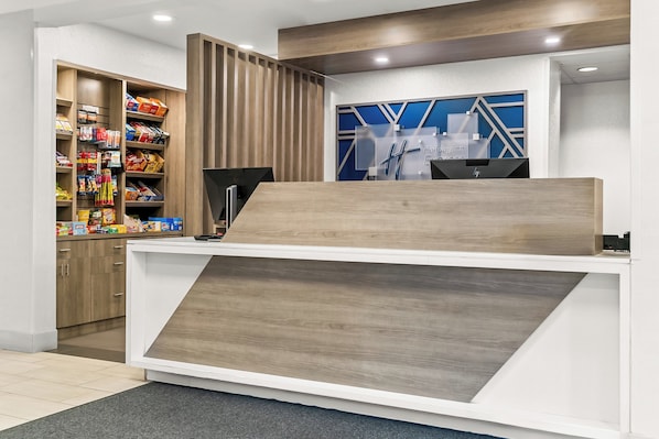 Een receptiebalie van een hotel, modern vormgegeven, met een houten balie en een blauwe wand met geometrische patronen.
