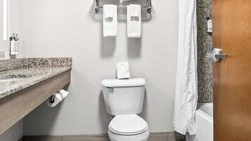 Une salle de bain moderne équipée de toilettes, d’un porte-serviettes, d’un rideau de douche et d’un plan de toilette en marbre.