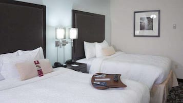 A hotel room with two beds, a nightstand, a lamp, and a framed picture on the wall.