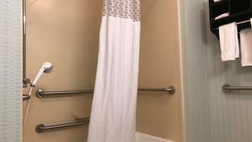 A bathroom with a bathtub, a shower curtain, and a towel rack with towels.