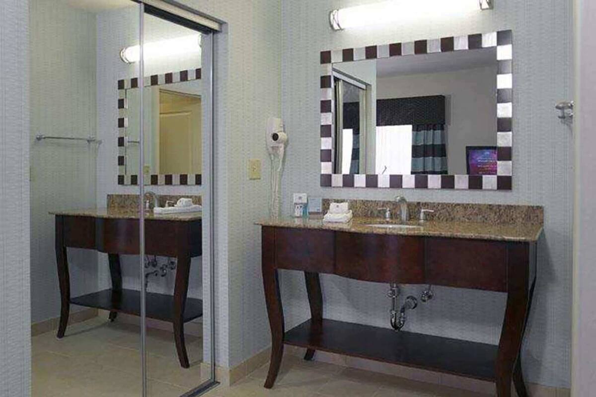 A bathroom with a mirror, sink, and toilet.