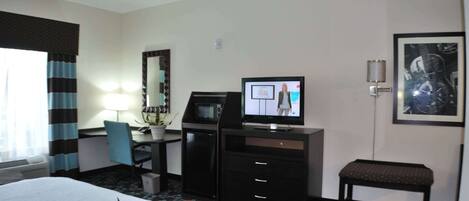 A hotel room with a bed, desk, TV, and a small bench.
