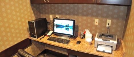 A small office space with a desktop computer, a printer, a telephone, and a chair.