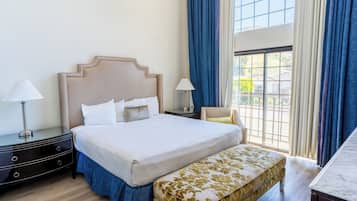 A neatly arranged hotel room with a large bed, bedside tables with lamps, a bench, and a view through a window.