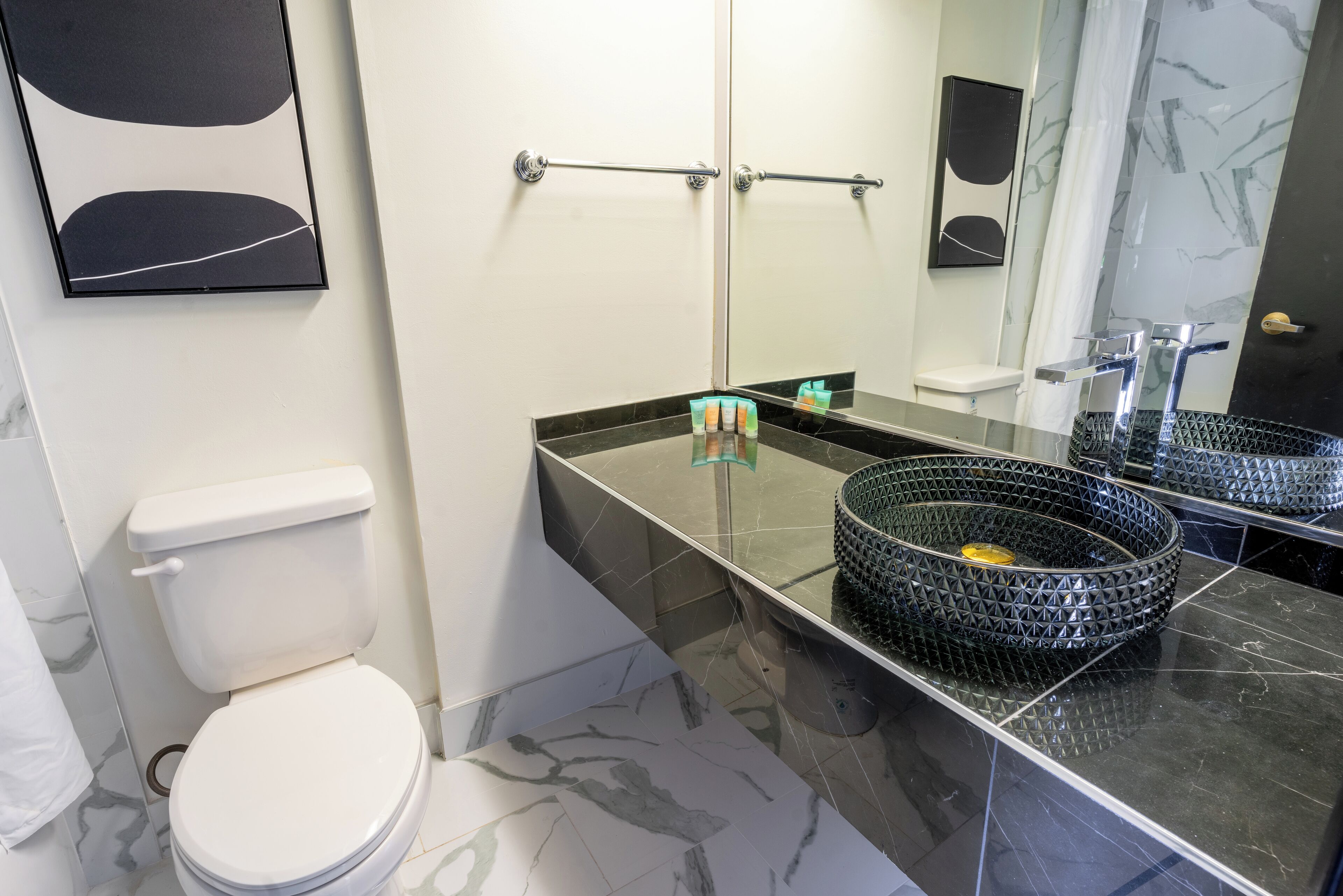 A modern bathroom with a toilet, a sink with a black countertop, and a mirror.