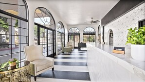 A hotel lobby with a reception desk, seating area, and large arched windows.