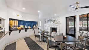 A modern dining area with a stone fireplace, a buffet counter with food items, and a seating arrangement with tables and chairs.