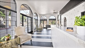 Hotellin aula, jossa on vastaanottotiski, oleskelualue ja suuret, kaarevat ikkunat.