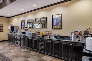 A hotel kitchen with a long counter, microwave, coffee maker, waffle maker, and various kitchen appliances.