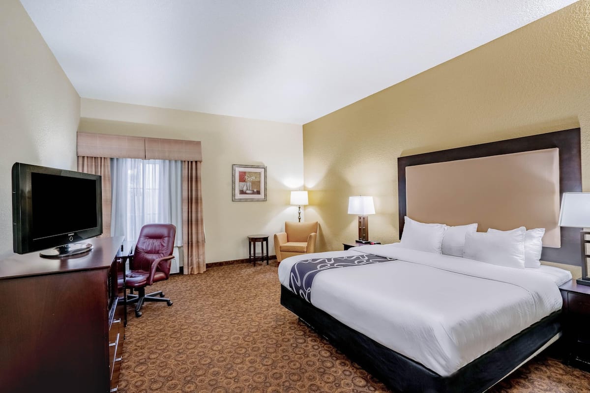 A hotel room with a bed, a TV, a desk, a chair, and a lamp.