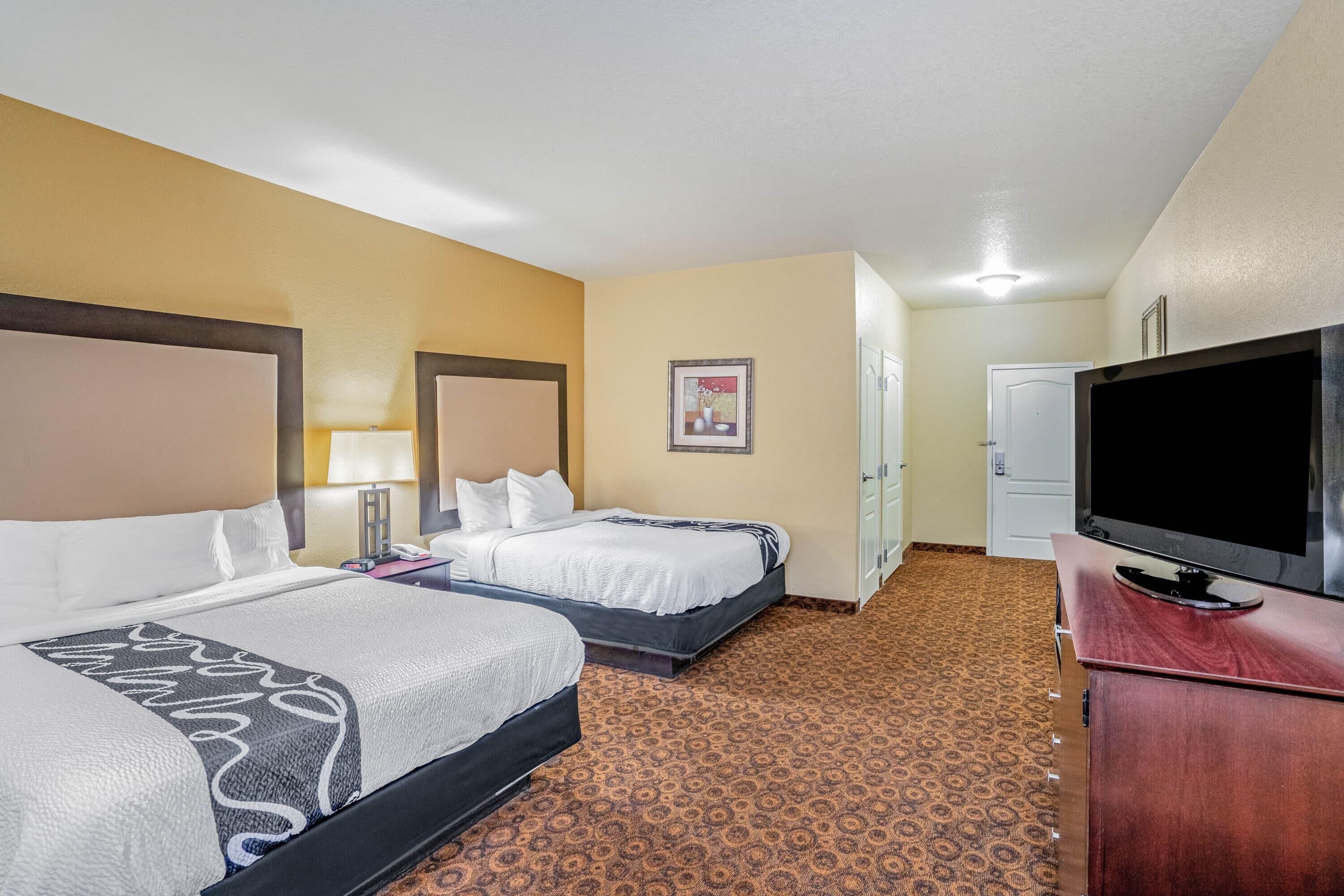 A hotel room with two beds, a television, a desk, and a wardrobe.