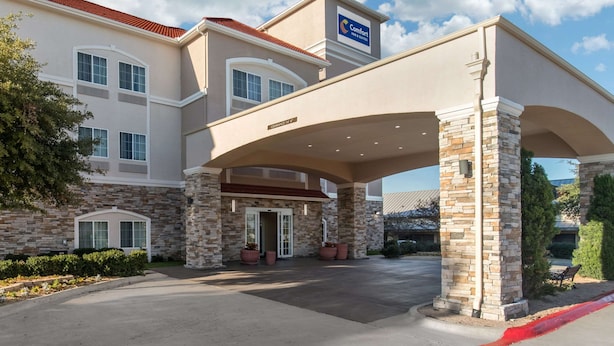 A hotel entrance with a covered walkway, stone facade, and a sign indicating it is a Comfort Inn & Suites location. - Comfort Inn & Suites Cedar Hill Duncanville (Cedar Hill)