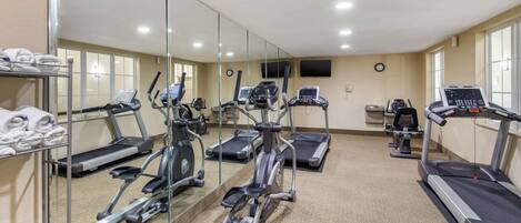 A gym with various exercise equipment, including treadmills, elliptical machines, and a stationary bike.