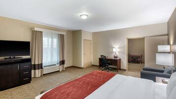 Ein Hotelzimmer mit Bett, Schreibtisch, Stuhl, Fernseher und einem Fenster mit Vorhängen.