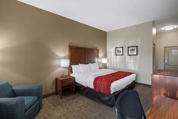 A hotel room with a bed, a desk, a chair, and a nightstand.