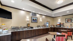 A hotel dining area with a buffet, seating, and a TV mounted on the wall. - Comfort Inn & Suites Cedar Hill Duncanville (Cedar Hill)