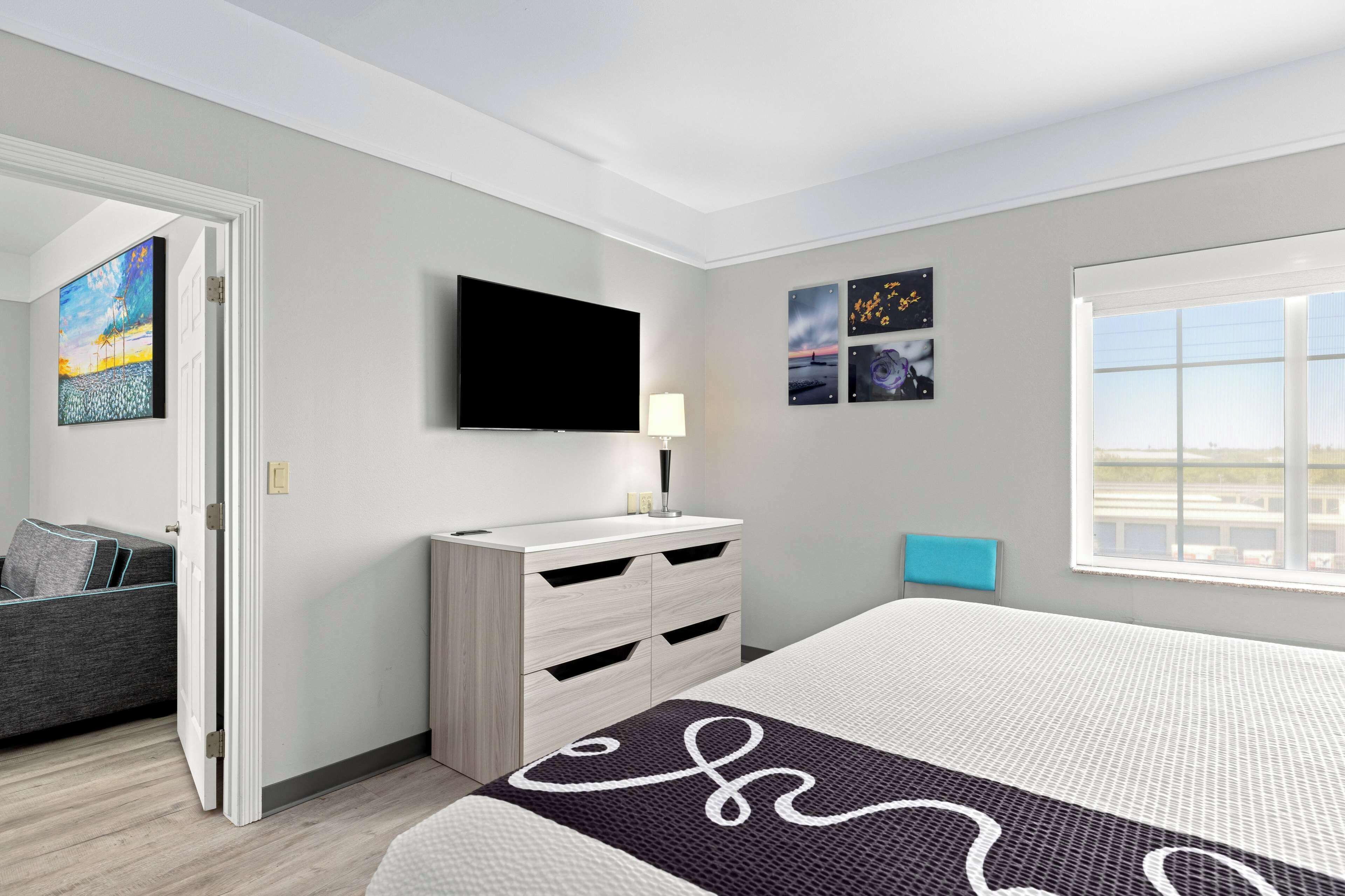 A modern bedroom with a bed, a TV, a dresser, and artwork on the walls.