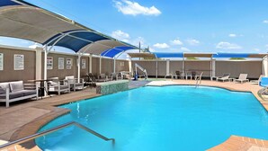 An indoor swimming pool with lounge chairs and sunshades. - La Quinta Inn & Suites by Wyndham Raymondville (Raymondville)