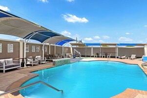 Una piscina al aire libre, sillones reclinables de piscina