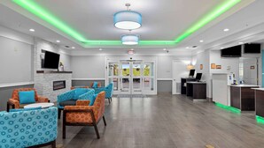 A spacious lobby with a reception desk, seating area with patterned chairs, and a fireplace. - La Quinta Inn & Suites by Wyndham Raymondville (Raymondville)